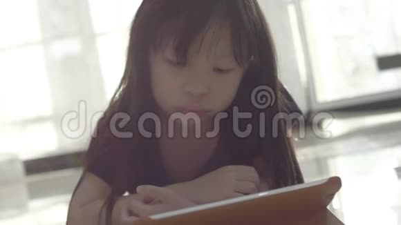 亚洲小女孩在家看数码平板电脑上的视频视频的预览图