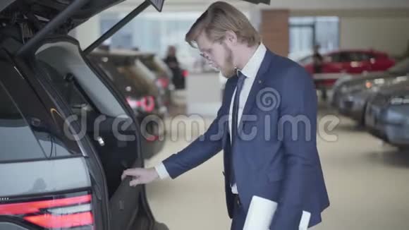 大胡子的商人选择汽车的汽车出现了近高个子男人拿着平板电脑看着打开的曲柄和检查视频的预览图
