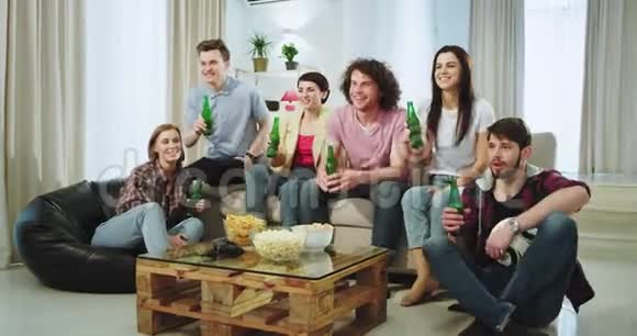 非常兴奋的朋友们准备在客厅中间的电视上看足球比赛他们喝啤酒视频的预览图