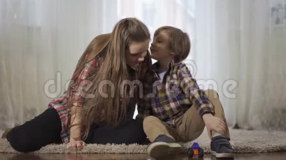 姐姐和弟弟一起玩坐在地板上毛茸茸的地毯上小男孩在窃窃私语视频的预览图