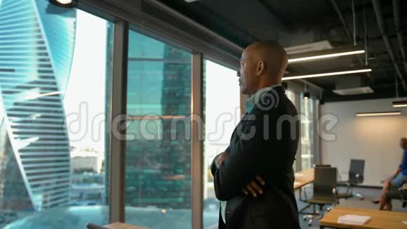美国黑人企业家站在巨大的现代办公室窗口附近表情严肃视频的预览图