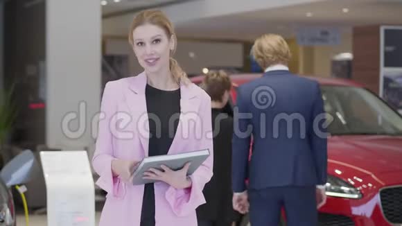 一幅穿着粉色夹克的讨人喜欢的女人的画像她在镜头中解释了关于汽车的信息手里拿着一本大书视频的预览图