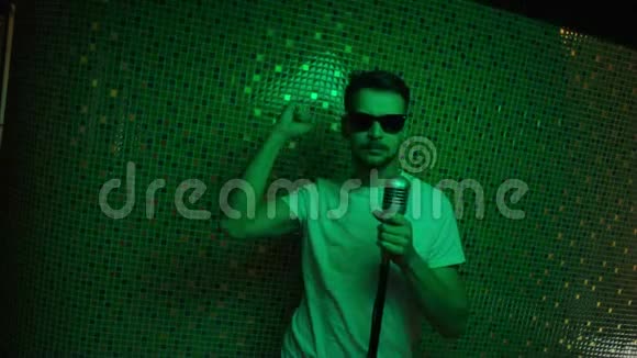成熟的男人戴着现代太阳镜和白色t恤跳舞拿着麦克风视频的预览图