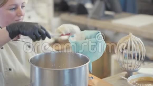 女糖果工统一把刚煮好的甜味混合物放入糕点袋中用来装饰蛋糕视频的预览图
