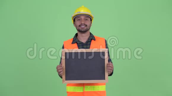 快乐的长着胡须的波斯建筑工人一边拿着黑板一边说话视频的预览图