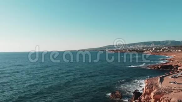 落基的悬崖被海洋蓝色清澈的水溅击中在地平线上形成白色的泡沫旅馆和度假胜地也在其中视频的预览图