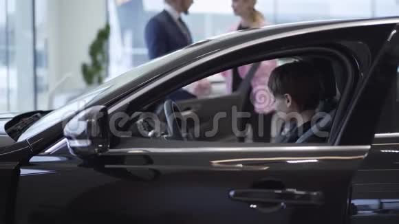 漂亮的女人短发坐在现代汽车的前景她年轻的母亲在和推销员谈话视频的预览图