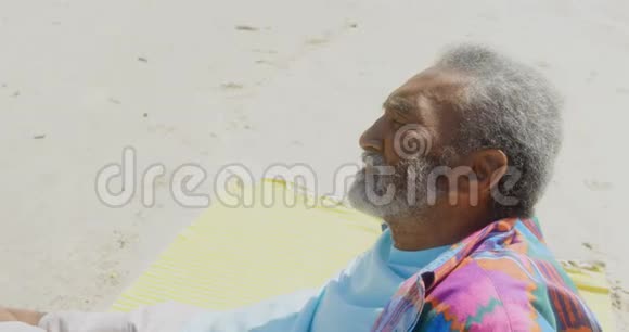 在4k的阳光下在海滩上放松的有思想的活跃的资深非裔美国人的景色视频的预览图