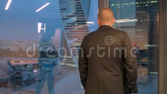 穿西装的成功商人双手插兜走在办公室里的完整背影视频的预览图