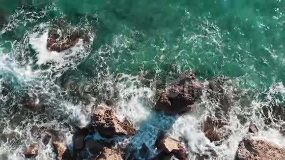 鸟瞰蓝色清澈海水海波的鸟瞰图蓝色的海浪波浪撞击岩石沙钻视频的预览图