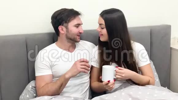 美好的早晨年轻夫妇在床上喝咖啡视频的预览图