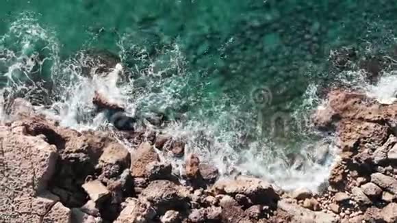 无人机沿着岩石海滩飞行美丽的海岸线有波浪大海岩的鸟瞰图大浪撞击海滨的俯视图视频的预览图