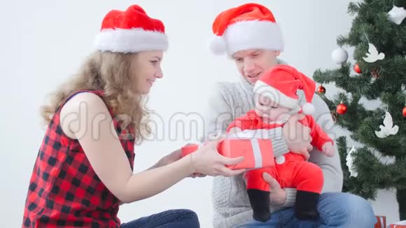 家庭假日和圣诞节的概念年轻的父母带着孩子打开圣诞礼物视频的预览图