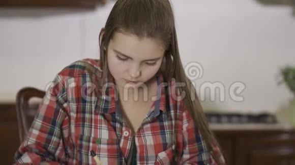肖像可爱的十几岁女孩坐在家里的桌子上做作业女学生把课文从视频的预览图