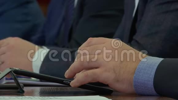 在一次商人会议上一名男子在平板电脑上打印指纹进行对话并做出公司决策视频的预览图