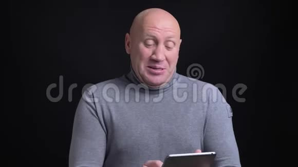 一张中年白种人的特写肖像他在平板电脑上播放一段情感视频背景是孤立的视频的预览图