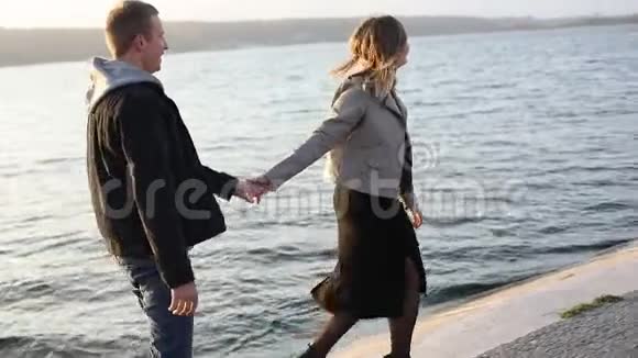 快乐的女孩带着她的男朋友在城市湖边散步视频的预览图