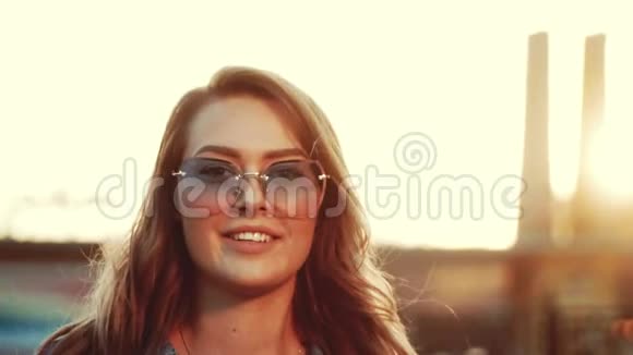 一个美丽的女孩微笑着戴着太阳镜走在街上享受着温暖的一天视频的预览图