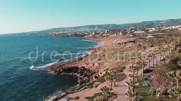 塞浦路斯珊瑚湾岩石海岸的顶部景观有棕榈树酒店和度假村强烈的海浪冲击着岩石海岸视频的预览图