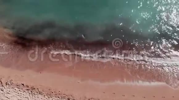 沙滩的鸟瞰图蓝色晶莹剔透的水无人机飞过美丽的海滩海浪创造泡沫无人驾驶视频的预览图