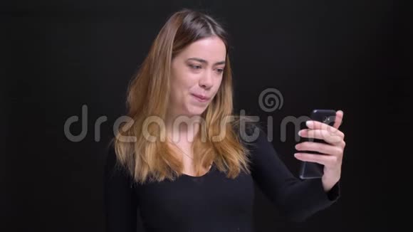 一位年轻美丽的白种人女性的特写照片她在电话里打了个视频随随便便地交谈着挥手告别视频的预览图