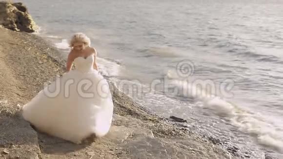 美丽可爱的新娘在海边漫步漂亮又整洁的女人金发天气晴朗婚礼视频的预览图