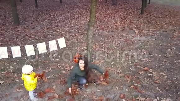 妈妈带着孩子在公园里的一片白纸叶子的花环上辗转着视频的预览图