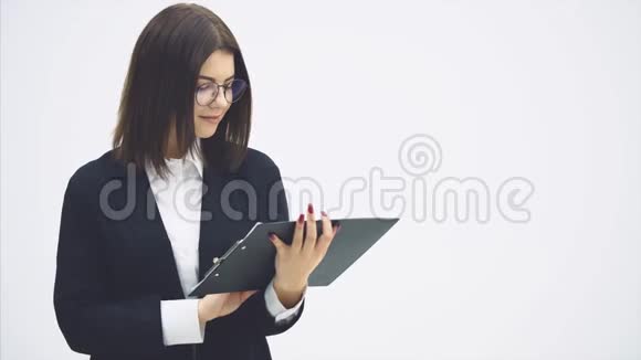 受启发的女商人穿着黑色西装手里拿着剪贴板把它转向相机微笑着单词视频的预览图