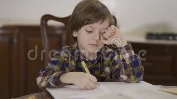 肖像小男孩坐在家里的桌子上有许多笔记本和文件孩子的学习作业视频的预览图
