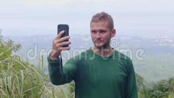 游客通过手机从山顶全景拍摄自拍照片旅游博主在手机上摆姿势视频的预览图