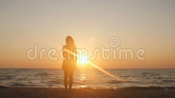 海岸上一个年轻女孩做轻操保健和运动关注女人伸展身体和放松的剪影视频的预览图