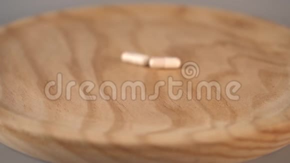 白色和棕色的医用胶囊落在灰色背景的木制表面上视频的预览图