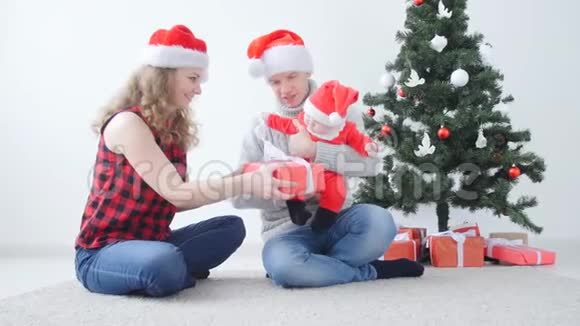 家庭假日和圣诞节的概念年轻的父母带着孩子打开圣诞礼物视频的预览图