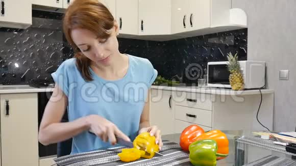 年轻的女人在厨房做沙拉的时候吃了一片黄铃椒健康的生活方式观念视频的预览图