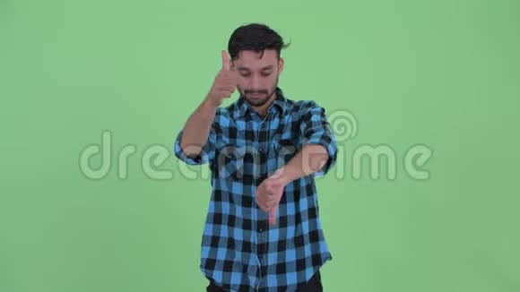 困惑的年轻留胡子的波斯时髦男人在竖起大拇指和竖起大拇指之间做出选择视频的预览图