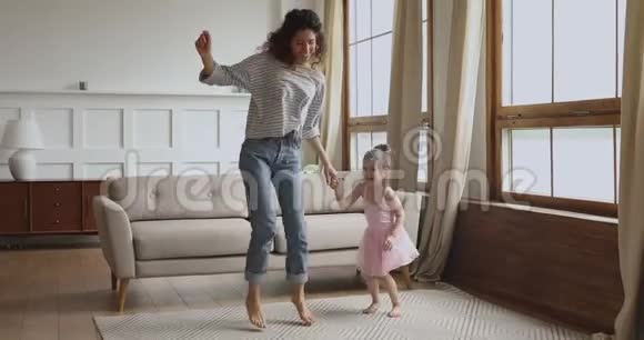 无忧无虑的快乐妈妈和小女儿在家跳舞视频的预览图
