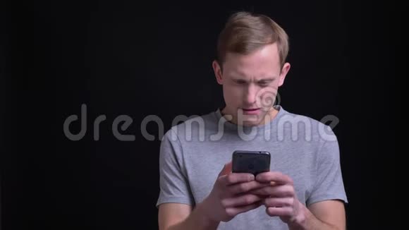 一位年轻英俊的白种人的特写肖像他用电话回应社交媒体上的帖子笑在面前视频的预览图