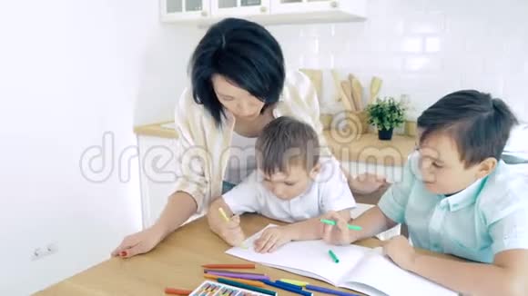 妈妈在厨房里帮两个儿子用纸笔画视频的预览图