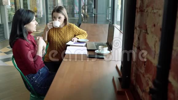 年轻女性在咖啡馆或办公室里聊天和喝咖啡视频的预览图
