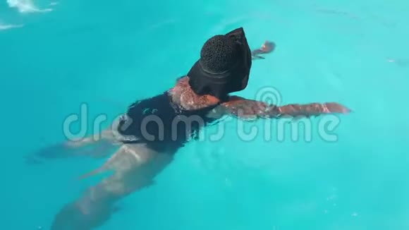 未被认出的戴黑帽子的老年女性在酒店的蓝色游泳池游泳娱乐的概念视频的预览图