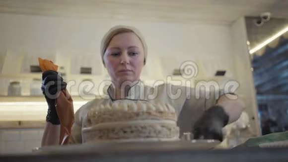 肖像经验丰富的糖果师穿着制服把刚煮好的甜点或奶油冻和糕点袋放在视频的预览图