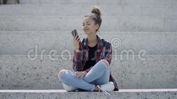 年轻漂亮的美国黑人女孩在户外用智能手机说话视频的预览图