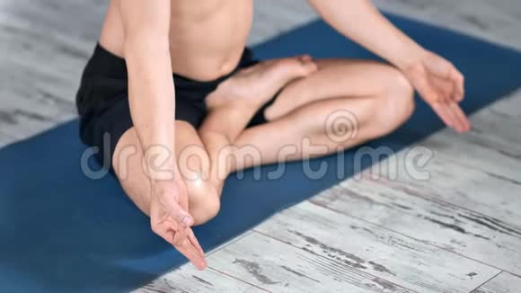 特写瑜伽男坐在垫子木地板上坐在莲花的位置练习呼吸冥想视频的预览图