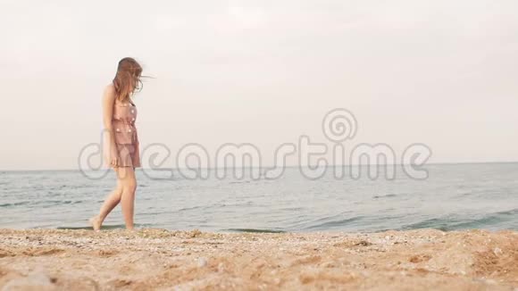 年轻女子正沿着海滨散步休闲度假的理念女孩在孤独中享受自然视频的预览图
