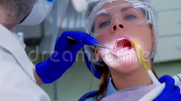 牙科医生在超声波清洗时使用唾液喷射器将水倒在女性牙齿上视频的预览图