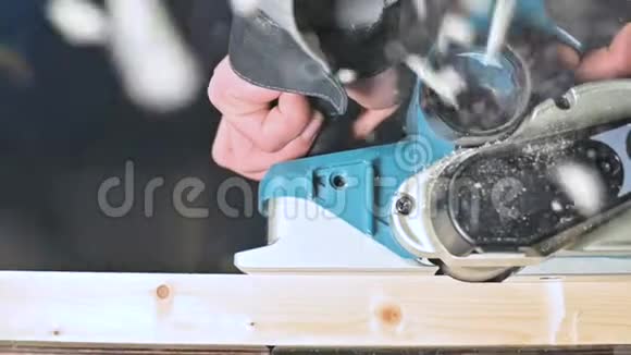 木工在家庭车间用电平面工作的手的特写在慢速运动中整理木制部件视频的预览图