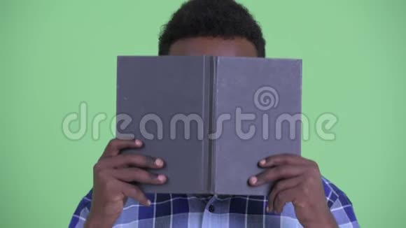 年轻的非洲时髦男人躲在书后面思考视频的预览图