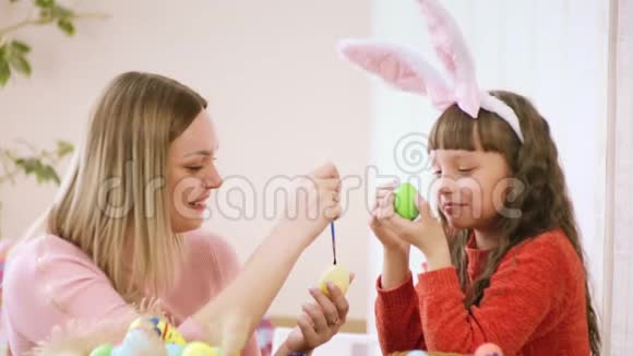 女儿和妈妈一起装饰鸡蛋然后用刷子互相挠痒痒鼻子他们笑得很厉害视频的预览图