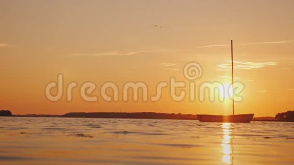 湖镜面上一艘孤独的渔船夕阳用橙光照亮一切视频的预览图
