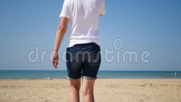 戴帽子的女孩正沿着沙滩走向大海视频的预览图